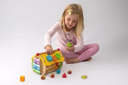 Child playing with a colourful wooden activity house for toddlers.